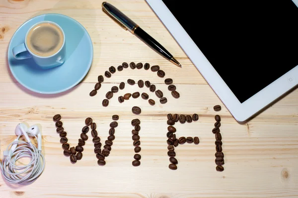 WiFi sembolü kahve çekirdekleri ile yaptı. Ahşap masa üstünde laptop — Stok fotoğraf