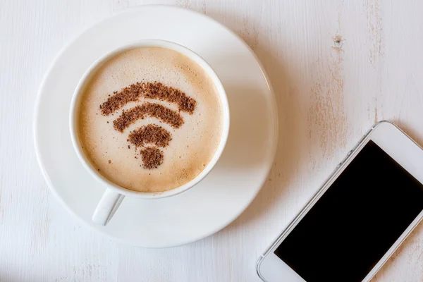 WiFi symbol gjord av kanel som kaffe dekoration i kopp cappuccino. Laptop på vit trä bakgrund — Stockfoto