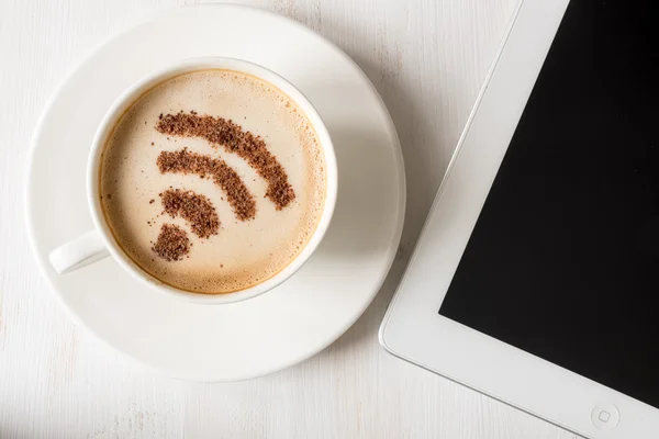 WiFi symbol gjord av kanel som kaffe dekoration i kopp cappuccino. Laptop på vit trä bakgrund — Stockfoto