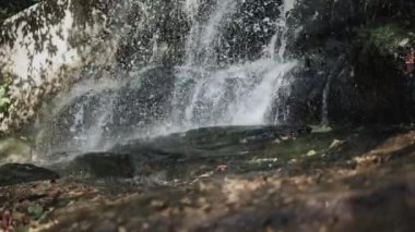 Dağlarda bir şelale, kayalardan akan su, şelaleden fışkıran su, doğada taşların üzerine dökülen su, büyük taşların üzerine dökülen su..