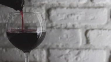 Kırmızı şarabı beyaz tuğladan bir arka planda şarap bardağına dök..