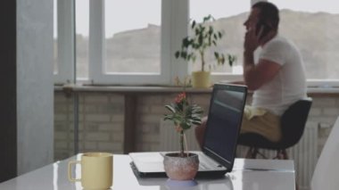 Dairede telefonla konuşan bir adam. Bir adam klavyeyle yazı yazıyor ve içki içiyor.