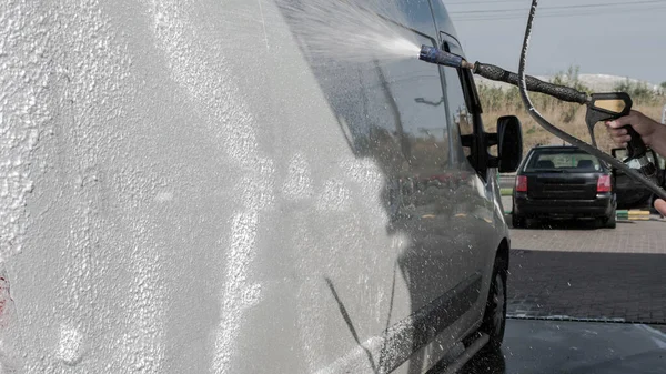 Car wash a car, a man washes a car, a man washes away dirt from a truck.