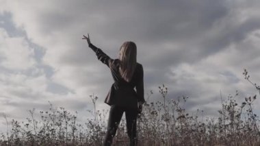 Doğadaki kız, güzel düşünceli bir kız gökyüzüne bakar, doğada uzun otların arasında durur.