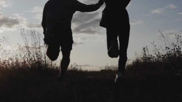 一个男人和一个女孩牵着手跑来跑去 一个女人和一个男人在日落时跑来跑去 — 图库视频影像