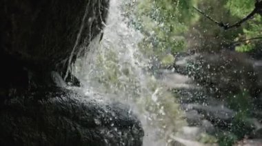 Kayaların üzerinde bir şelale, taşların üzerinde bir su damlası, taşların üzerinde bir dağ nehri akıyor, güzel damlalar, su damlaları