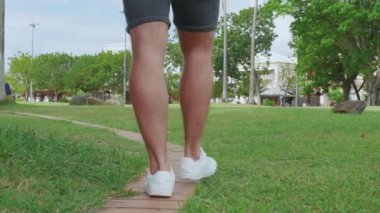 Bir adam yolda yürüyor, yalnız bir adam. Üzgün adam, parkta çimlerin üzerinde yürüyen genç adam..