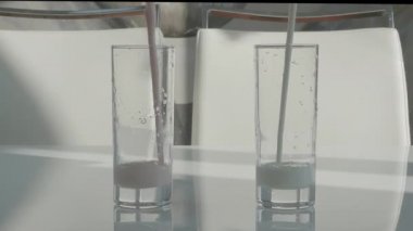 Meyve yoğurdunu beyaz bir masaya koy, süt ürünlerini bardaklara doldur.