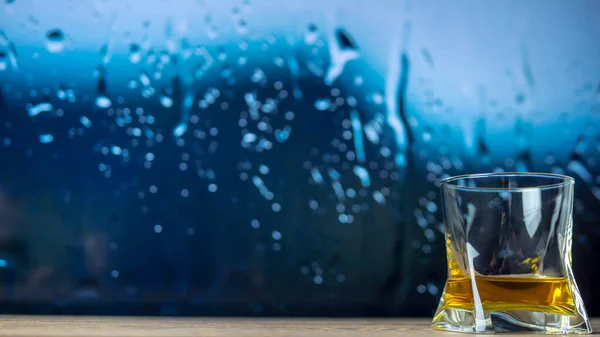 알코올의 배경이 비오는 창문을 배경으로 유리잔에 위스키 — 스톡 사진
