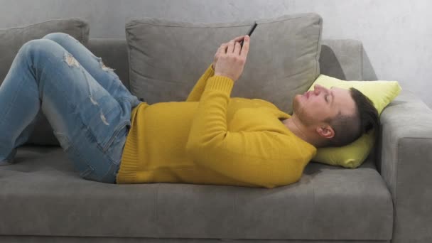 Muž Leží Gauči Píše Smartphone Muž Mluví Online Přáteli Mladý — Stock video