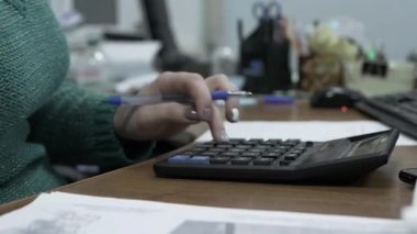 Manikürlü kadın eller hesap makinesine yazıyorlar. Bütçeyi, kız muhasebeciyi ve mali durumu saymak için hesap makinesine güveniyorlar.