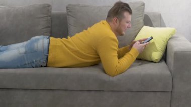 Bir adam akıllı telefonuyla yazı yazıyor, genç bir adam internetteki arkadaşlarıyla iletişim kuruyor, bir adam elinde akıllı telefonuyla kanepede uzanıyor. Uzaklık öğrenme kavramı