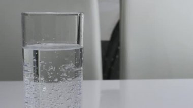 Kar beyazı arka planda cam bir şişede maden suyu kabarcıkları, yakın plan bir bardak maden suyu.