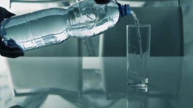 İçme suyu, bardağa su dökmek, beyaz bir masada bardakta maden suyu dökmek.