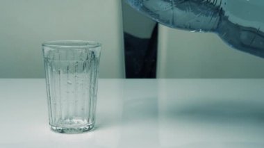 İçme suyu plastik şişeden bardağa dökülür. Doğal suyu bardağa dök.