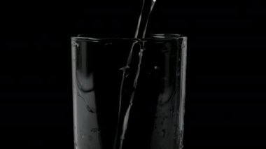 Siyah arka planda bir bardakta maden suyu, köpüklü su içmek, bardağa su dökmek.