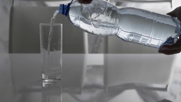 プラスチックボトルからガラスへの水の流れ ミネラルウォーターはガラスに注がれ 人は飲料水 ストリームを注ぐ — ストック動画