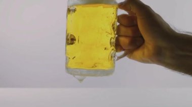 Erkek eli bir bardak bira kaldırır. Beyaz arka planda. Yakın plan.