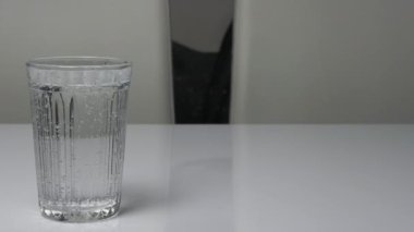 Beyaz bir mutfak masasında bardakta su içmek, köpüklü maden suyu, bardak içme suyu ile doludur..