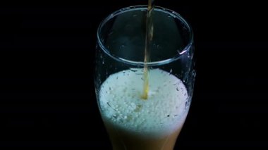 Soğuk birayı bardaklara dolduruyorum. Siyah arka plan. Köpüklü taze bira. Güzel bir bira akıntısı.