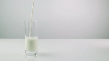 Bir adam şeffaf bir bardağa taze kefir döker, beyaz arka planda beyaz bir süt ürünü. Yakın plan. Taze yoğurt. Şişeden bardağa kefir dök.