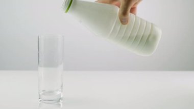 Beyaz arka planda cam bardakla plastik şişeden süt, süt ürünü, bardakta yoğurt.