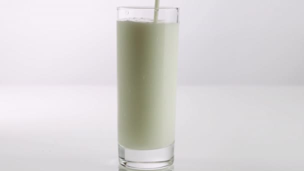 逆方向にケフィアの流れ ガラスの中のミルク ヨーグルトのストリーム 白い背景に — ストック動画