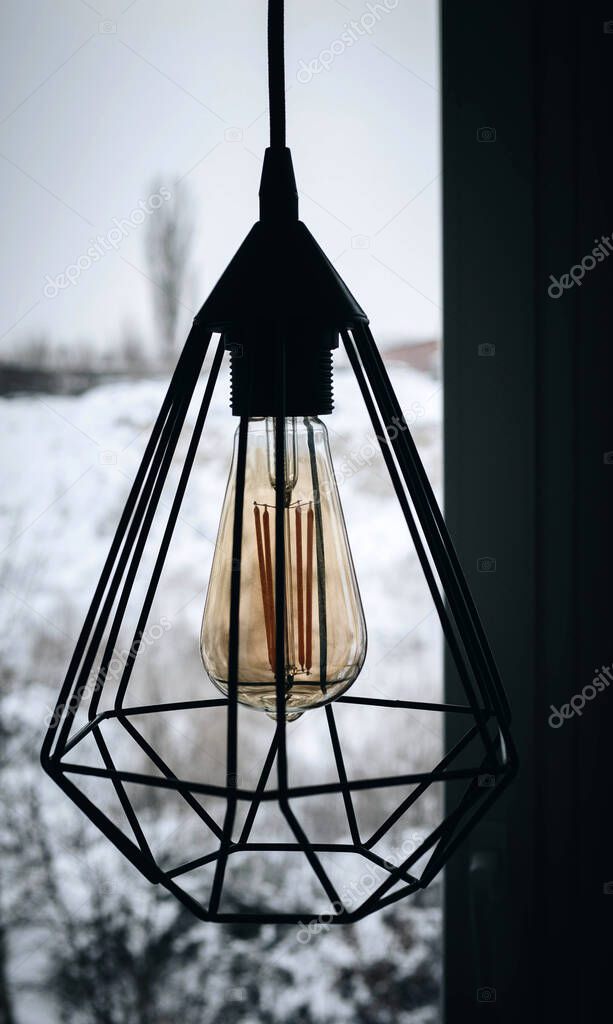 Loft lamp on the background of winter outside the window, incandescent lamp, modern lamp. Hanging lamp