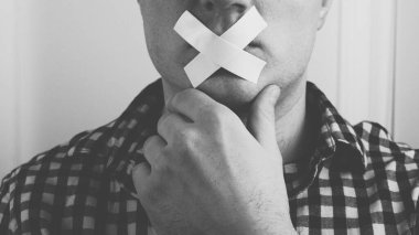 Ağzına bant bantlanmış bir adam, ağzında yapıştırıcı bandıyla siyah beyaz bir adam resmi.