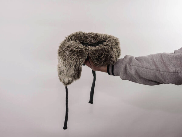 A homeless man asks for money holding a hat in his hand on a white background, a place to insert a product into a hat with earflaps, a man asks for money.