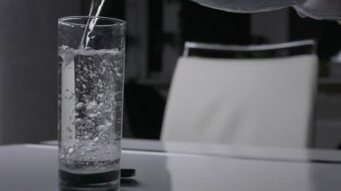 Bir bardağa maden suyu dök, köpüklü su iç. Suyu olan şeffaf cam.