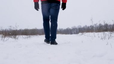 Karla kaplı bir patikada yürüyen bir adam, buzda kayıp düşen bir adam, turuncu kışlık ceketli bir adam etrafına bakıyor. Yalnız adam..