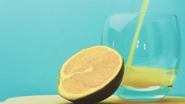 青い背景に黄色のレモネードをグラスに注ぐ フルーツオレンジドリンク ソフトフォーカス — ストック動画