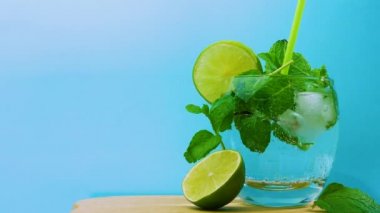 Naneli ve limonlu alkollü kokteyl, yakın plan bir pipet, şeffaf bardakta köpüklü bir mojito. Yaz içeceği