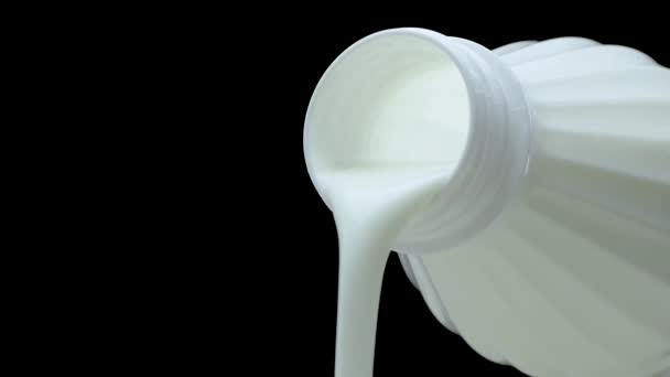 牛乳は黒の背景に流れ 牛乳を注ぎ ボトルから新鮮なヨーグルトを注ぎます 牛乳製品牛乳のジェットのクローズアップ — ストック動画