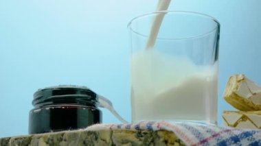 Sütlü bir hayat, şeffaf bir bardağa taze süt dökmek, hamur işleri ve tahta tahtada sütle reçel.