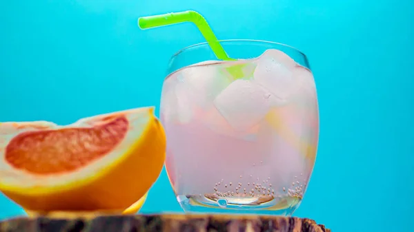Fruit tropical alcoholic drink, cocktail on a bright colorful background with a slice of grapefruit. Alcoholic drink in a glass on a wooden rack