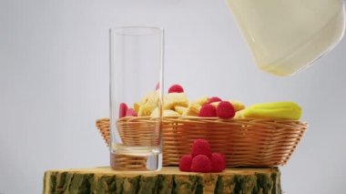 Pour fresh milk into a glass on a black background, dairy products with fruits in a basket, white fruit yogurt.