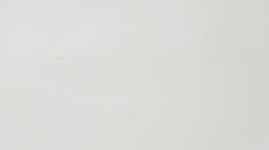 A drop of fresh milk falling into the milk. Slow motion. A drop of milk or a white drop of liquid