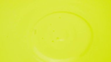 A drop of acrylic paint gets into the paint. Yellow colorful blob background. Aqua colorful yellow abstraction