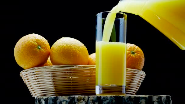Orangensaft Ein Glas Auf Schwarzem Hintergrund Gießen Frische Orangen Korb — Stockvideo