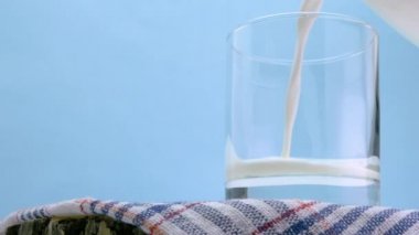  Açık mavi zemin üzerinde tahta bir tahtaya süt dök. Süt ürünü