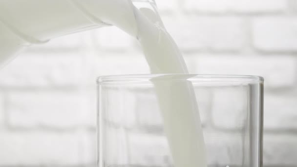 Крупним Планом Заливання Молока Глечика Склянку Фоні Білої Цегляної Стіни — стокове відео