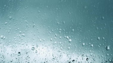 Arka plan yağmurlu, damlalar camdan akıyor, pencerenin dışında yağmur yağıyor, fırtına var. Şeffaf camlara yağmur damlaları