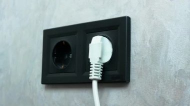 Güç kaynağından bağlantıyı kes ve fişi çek. Beyaz kapaklı siyah duvar soketi.