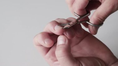 Yakın plan. Tırnak makası yardımıyla tırnak kesen, tırnaklarını kesen bir adam. Bir adam tırnaklarını kesiyor.