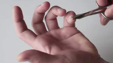 Tırnaklarını kesmek için tırnak makası kullanan, küçük parmağındaki tırnağı kesen bir adamın yakın çekimi..