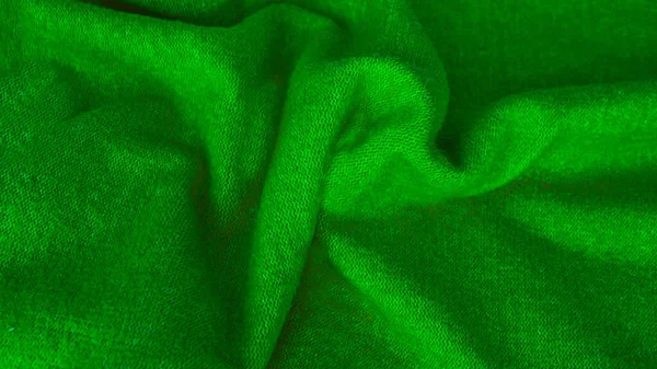 Background with wavy lines from natural silk fabric of green color. Green fabric background. Background from silk fabric. Copy space