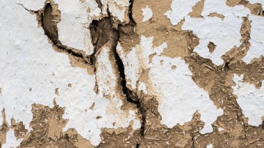 Bölünmüş duvarın dokusu çok eski. Çamur ve samandan bir duvar. Kulübe eski. Kırıkları olan eski bir duvarın boyasını soymak..