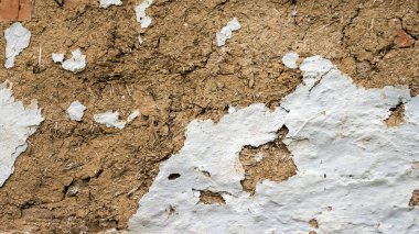 Kulübenin dokusu eskimiş. Çamur ve samandan eski bir duvar. Eski bir evin eski duvarı. Arka planda soyulmuş duvar boyası..